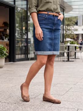 A mid-length denim skirt combined with a tucked-in olive green utility blouse and gold dainty jewelry to complement the warm tones of the leopard print.