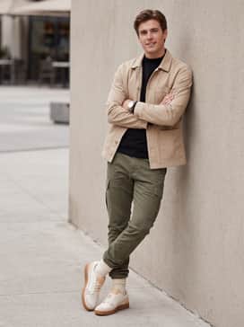 Indoor Special – Slim-fit olive green cargo pants with a black mock-neck long-sleeve tee and a beige canvas chore coat for a functional, utility-driven outfit.