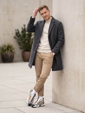 Relaxed-fit khaki chinos, a tucked-in cream mock-neck sweater, and a navy wool overcoat for a sophisticated high-low streetwear aesthetic.
