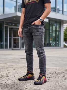 Ja 3 – Distressed black slim-fit denim paired with an oversized vintage graphic tee featuring gold and red lettering for a cohesive streetwear vibe.