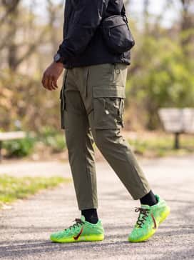 Ja 3 Spooky Season – A tactical utility look using olive green cargo pants with strap details, a black technical windbreaker, and a minimalist black crossbody bag to keep the focus on the footwear.