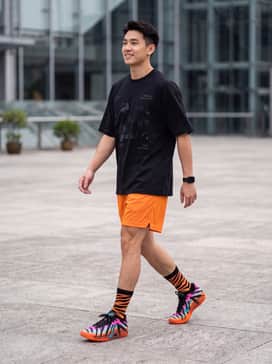 Ja 3 Tristate – A black oversized graphic t-shirt paired with bright orange mesh basketball shorts and black mid-calf socks for an authentic on-court aesthetic.