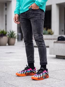 Ja 3 Tristate – Distressed charcoal skinny jeans, a neon teal windbreaker, and a black snapback cap to highlight the shoe's vibrant accent colors.