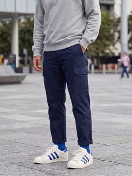 Navy blue utility cargo pants with an oversized grey heathered sweatshirt and a matching blue baseball cap for a modern street-focused look.