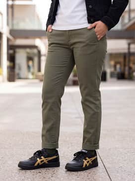Straight-leg olive chinos and a crisp white t-shirt tucked in, layered with a black denim jacket for a classic, rugged streetwear aesthetic.