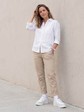 Beige tapered chinos and a crisp white linen button-down shirt for a clean, sophisticated smart-casual look suitable for a creative office environment.
