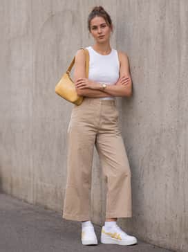Wide-leg beige trousers and a tucked-in ribbed tank top, finished with a yellow baguette bag for a sophisticated yet comfortable city outfit.