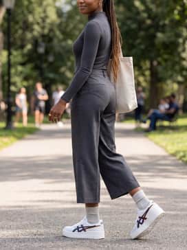 Cropped wide-leg trousers in charcoal grey paired with a fitted mock-neck bodysuit for a sleek, modern urban aesthetic that highlights the chunky footwear.