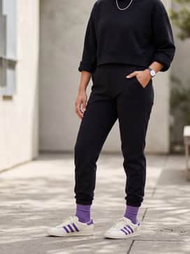 Tailored black joggers paired with a matching black cropped hoodie and a sleek silver chain necklace for an elevated athleisure aesthetic.