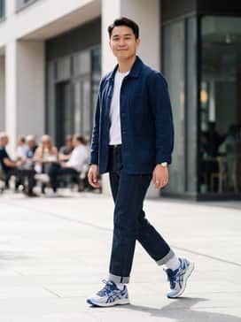 Straight-leg raw denim jeans paired with a crisp white t-shirt and a navy blue chore jacket for a timeless, functional look.