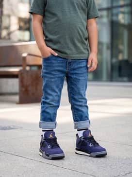 Dark-wash cuffed denim jeans worn with a mustard yellow graphic t-shirt to make the yellow branding on the shoe pop.