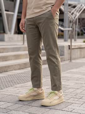 Slim-fit distressed light-wash denim jeans combined with a white waffle-knit long-sleeve shirt and an unbuttoned flannel in earth tones to complement the tan leather.