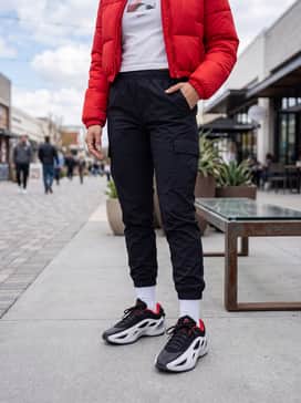 Streetwear Edge: Black nylon cargo joggers with bungee-cord cuffs, a cropped white graphic baby tee, and a red cropped puffer jacket to pull the color theme together.