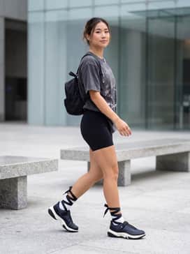 Jordan Pointe – High-waisted black biker shorts paired with an oversized vintage-wash graphic tee, silver chain accessories, and a mini nylon backpack for a balanced edgy streetwear look.