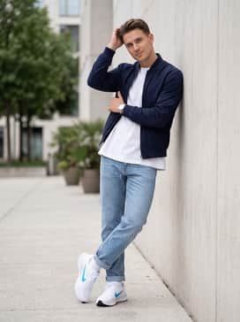 A casual weekend outfit with light-wash slim-fit denim jeans rolled at the ankle to show off the shoe's silhouette, paired with a crisp white oversized graphic tee and a navy bomber jacket.
