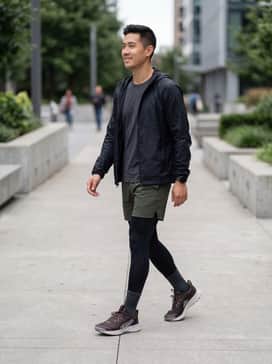 Juniper Trail 3 – Black moisture-wicking compression leggings under olive green 5-inch running shorts, paired with a charcoal grey technical t-shirt and a lightweight windbreaker for a high-performance athletic look.