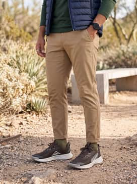 Juniper Trail 3 – Tan ripstop outdoor trousers with a tapered fit, a forest green merino wool base layer, and a quilted navy puffer vest for a functional mountain-ready outfit.