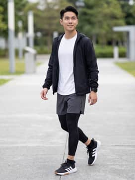 High-performance look featuring black moisture-wicking compression tights under charcoal grey running shorts, paired with a fitted white tech-fabric t-shirt and a lightweight black windbreaker.
