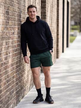 Athletic mesh shorts in forest green coordinated with a black graphic hoodie and high-performance crew socks for a classic gym-ready look.