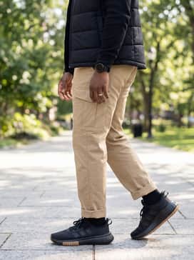 Cuffed khaki cargo pants worn with a black long-sleeve thermal top and a quilted vest for a rugged, outdoor-inspired casual outfit.