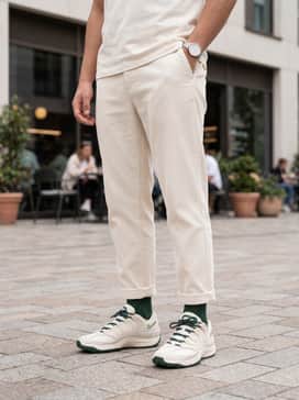Distressed light-wash relaxed-fit denim jeans, a simple white heavyweight cotton t-shirt, and a dark green baseball cap to match the shoe's accents.