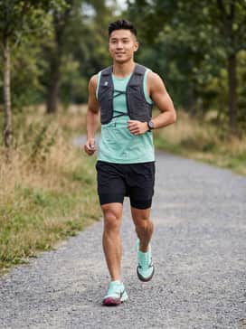 Kiger 10 – A technical trail-running kit featuring black compression liners under mint-green moisture-wicking shorts, paired with a matching mint sleeveless jersey and a charcoal grey hydration vest.