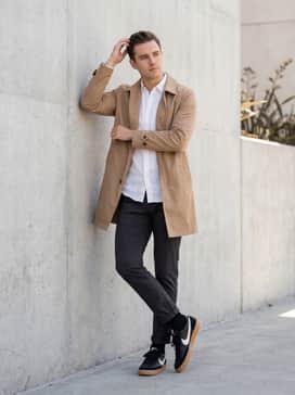 Black slim-fit trousers, a tucked-in white oxford shirt, and a tan trench coat to match the gum sole's warmth.