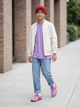 A coordinated street look featuring baggy light-wash denim jeans, a white oversized graphic tee, and a red beanie that complements the shoe's swoosh.