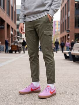 A trendy school outfit with olive green cargo joggers, a heather grey fleece hoodie, and white crew socks pulled up to showcase the gum sole.