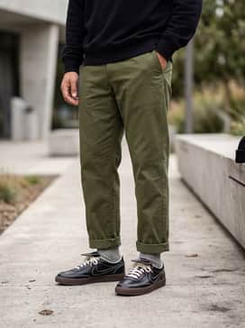 Tapered olive green chinos paired with a heather grey crewneck sweatshirt and a black beanie for a refined streetwear ensemble.