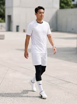 A professional match-day kit featuring a crisp white performance jersey with black side-venting, paired with matching white athletic shorts and high-tension black football socks.