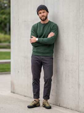Slim-fit dark wash jeans with a single cuff to highlight the unique laces, worn with a black crewneck sweatshirt and a matching olive beanie.