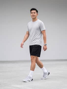 High-performance on-court look featuring black mesh basketball shorts, a light grey moisture-wicking compression top, and white crew-length performance socks to highlight the low-top silhouette.