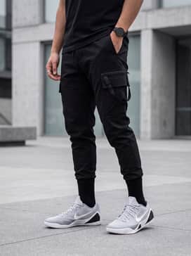 Kobe Ix Elite Low Em Protro – A sleek techwear-inspired outfit consisting of black tapered cargo joggers with strap detailing, a charcoal oversized hoodie, and a minimalist utility vest for an urban aesthetic.
