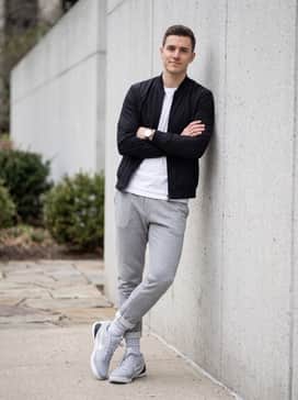 Clean casual streetwear pairing slim-fit grey fleece joggers with a crisp white premium cotton t-shirt and a lightweight black bomber jacket for a balanced, monochromatic vibe.