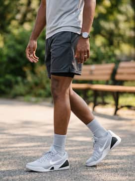 Kobe Ix Elite Low Em Protro – Summer athletic style with breathable charcoal mesh shorts, a graphic tee featuring minimalist branding, and a grey baseball cap to complement the shoe's primary color theme.