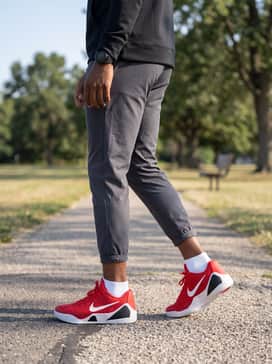 Kobe Ix Elite Low Em Protro – A sleek athleisure vibe with charcoal grey technical track pants, a fitted black quarter-zip pullover, and a matching red sports watch.