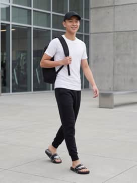 Style with black tech-fleece joggers, a fitted white moisture-wicking tee, and a black athletic cap for a sleek post-gym recovery outfit.