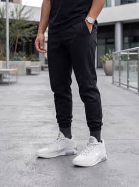 An urban tech-wear ensemble consisting of black tapered utility joggers, a charcoal grey tech-fleece hoodie, and a minimalist waterproof shell jacket for a functional, modern vibe.