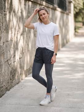 A dynamic training outfit with charcoal compression leggings worn under matching mesh gym shorts, topped with a fitted white moisture-wicking graphic tee for high-intensity sessions.