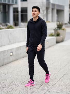 A sleek pair of black tech-fleece joggers paired with a matching black quarter-zip performance top to make the vibrant pink shoes the focal point.