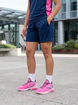 Breathable mesh basketball shorts in a dark navy blue with a coordinated pink-accented jersey and high-top white athletic socks.