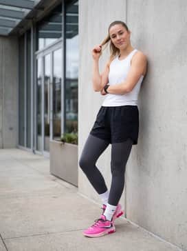 High-waisted compression leggings in charcoal grey combined with a cropped white performance tank and a lightweight pink windbreaker for a cohesive training look.