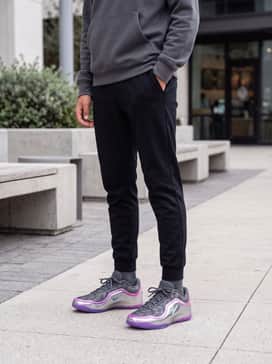 A streetwear-inspired outfit consisting of tapered black technical joggers, a metallic silver oversized hoodie, and a minimalist grey windbreaker for a futuristic urban aesthetic.