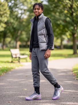 A coordinated athleisure ensemble with heathered grey fleece sweatpants, a fitted black performance quarter-zip, and a silver puffer vest for a sleek, monochromatic winter style.