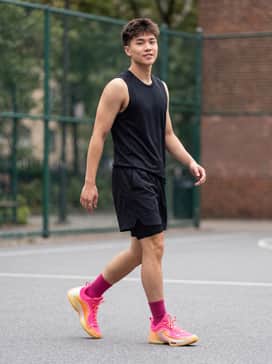 Performance Court Look: Black moisture-wicking basketball shorts paired with a sleeveless white compression jersey and fuchsia crew-length socks.