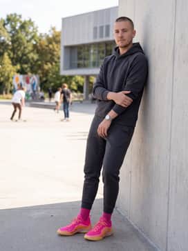 Coordinated Athleisure: Tapered charcoal tech-fleece joggers and a matching fitted hoodie with neon pink drawstring accents.