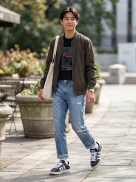 Distressed light-wash straight-leg jeans paired with a tucked-in oversized black graphic tee and a simple canvas tote.
