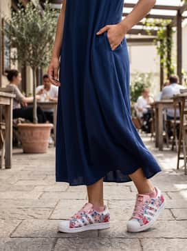 Liberty London Superstar Ii Shoes – A navy blue flowy midi dress combined with a cropped denim jacket, creating a balanced contrast between the solid dark fabric and the bright floral pattern of the sneakers.