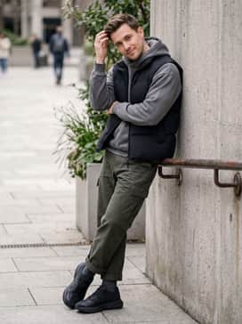 Loose-fit olive green cargo pants layered with a grey oversized hoodie and a black puffer vest to emphasize the shoe's rugged, technical design.
